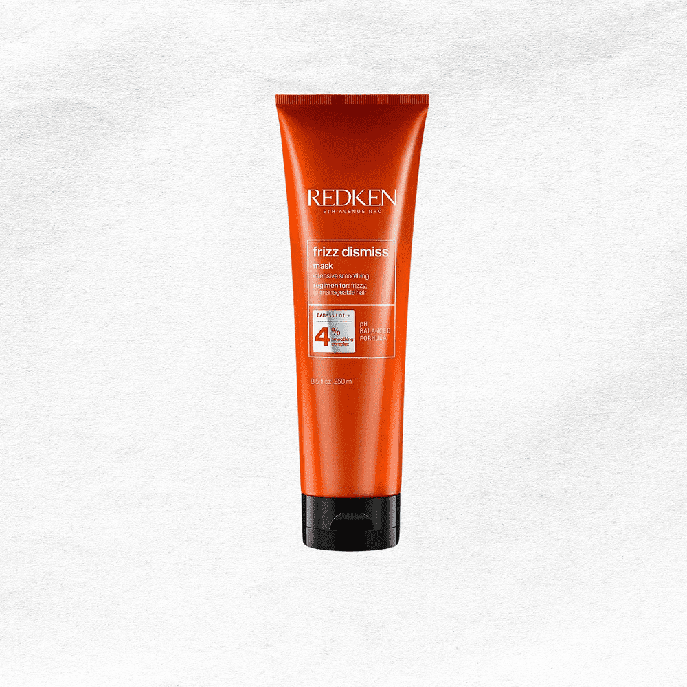 Redken Frizz Dismiss smoothing control cream in an orange tube on a white background.